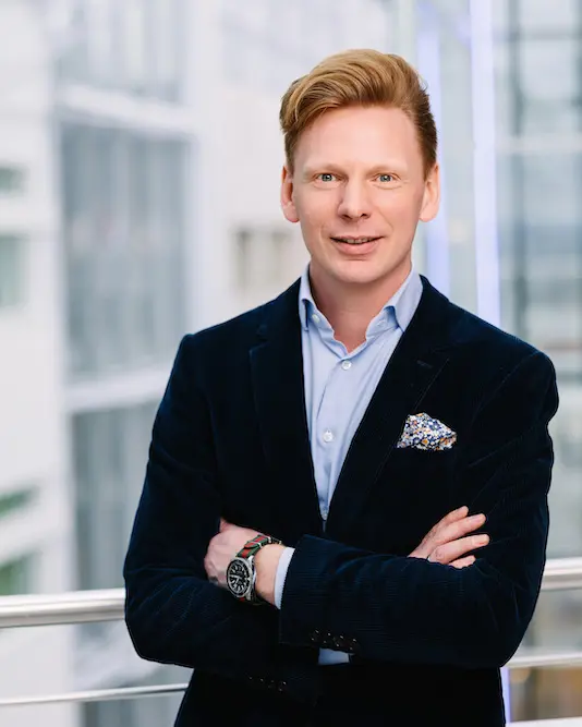 En person i dress som står foran en bygning