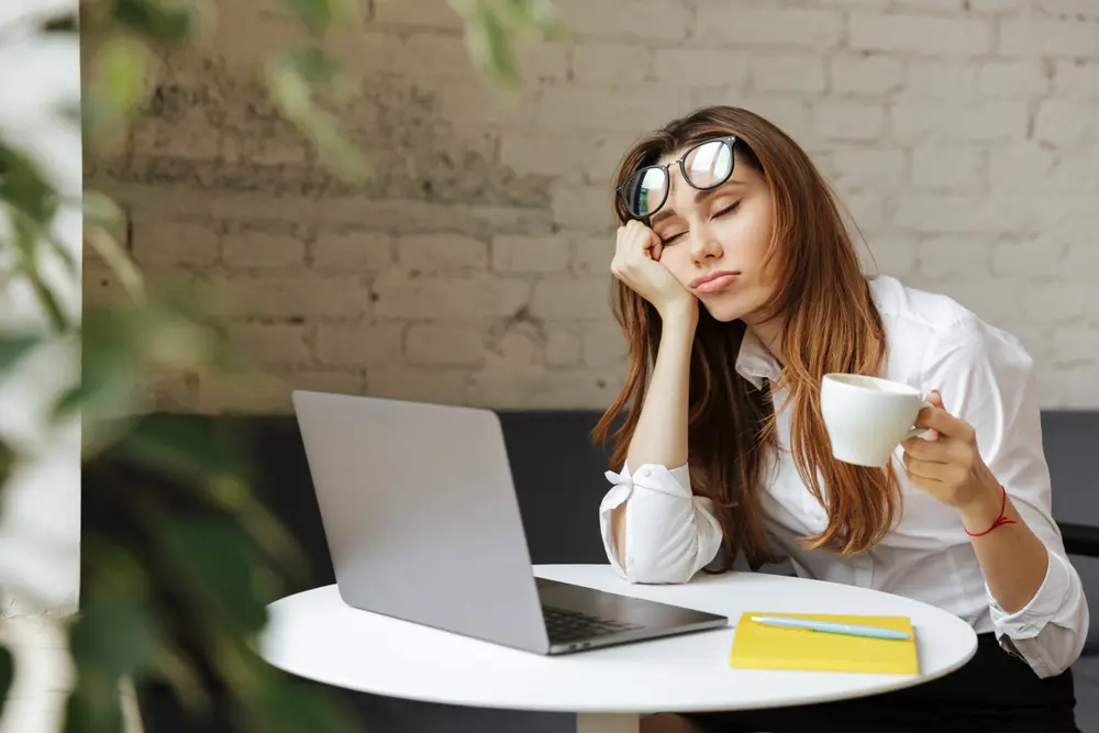 A woman sitting at a table with a laptop and a cup of coffee