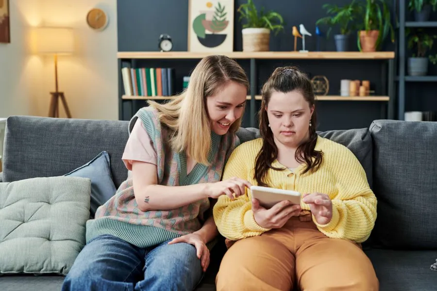 En kvinne og en jente som sitter i en sofa og leser en bok