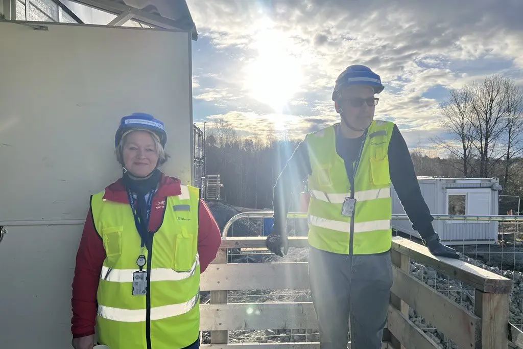 En mann og kvinne iført sikkerhetsvester og stående på en balkong