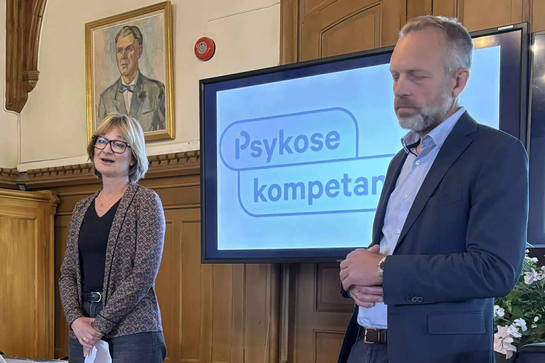 En mann og en kvinne som står foran et skilt