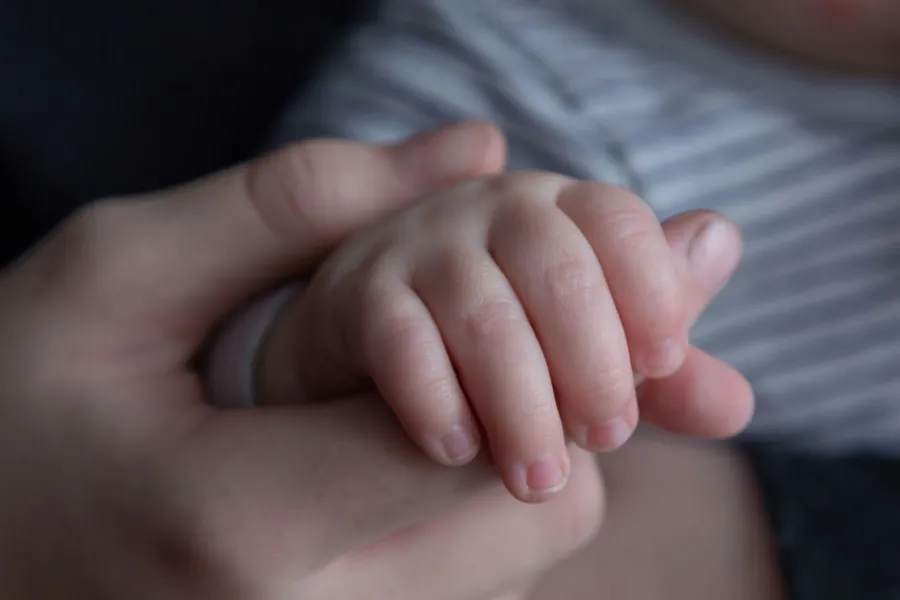 Et nærbilde av en person som holder en babys hånd