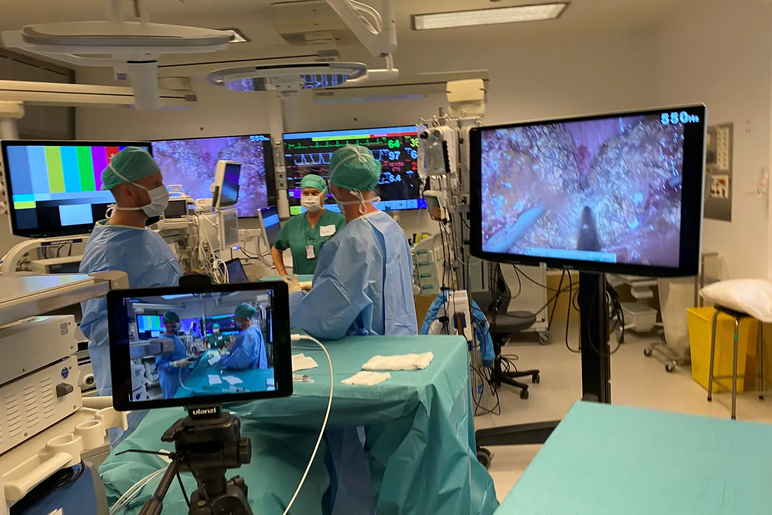 Bilde fra Intervensjonssenteret på Rikshospitalet med tre kirurger og monitorer og tv.