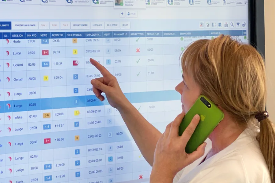 En som snakker i mobiltelefon og peker på en skjerm.