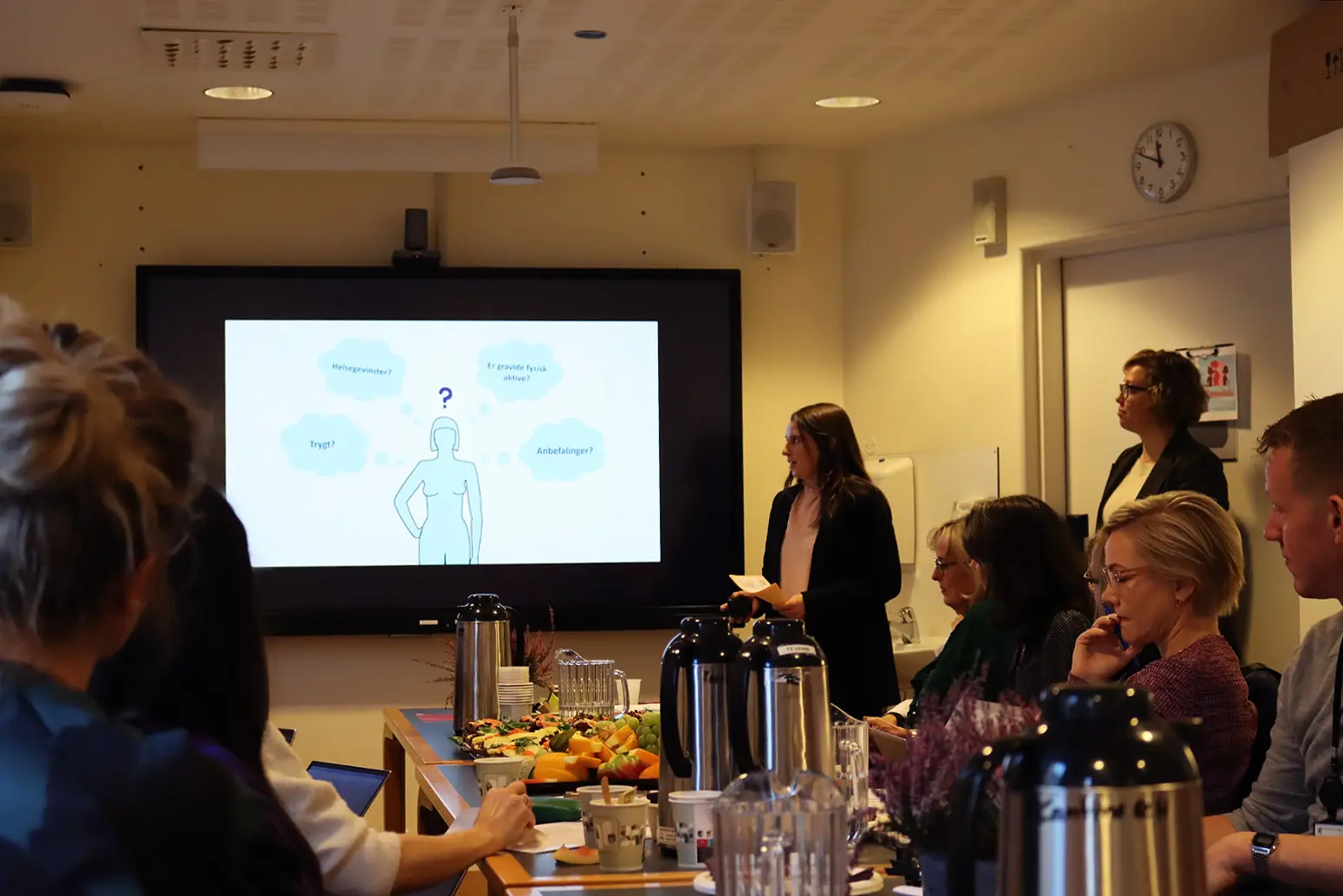 En gruppe mennesker som sitter rundt et bord og ser på en TV