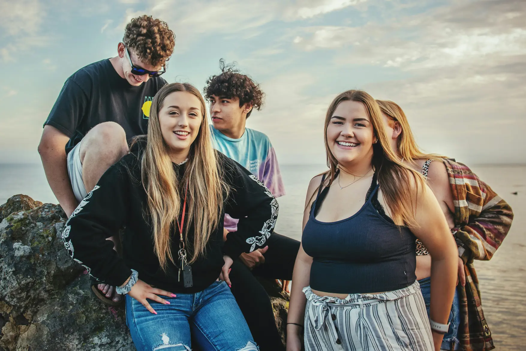 En gruppe mennesker som poserer for et bilde på en steinete strand
